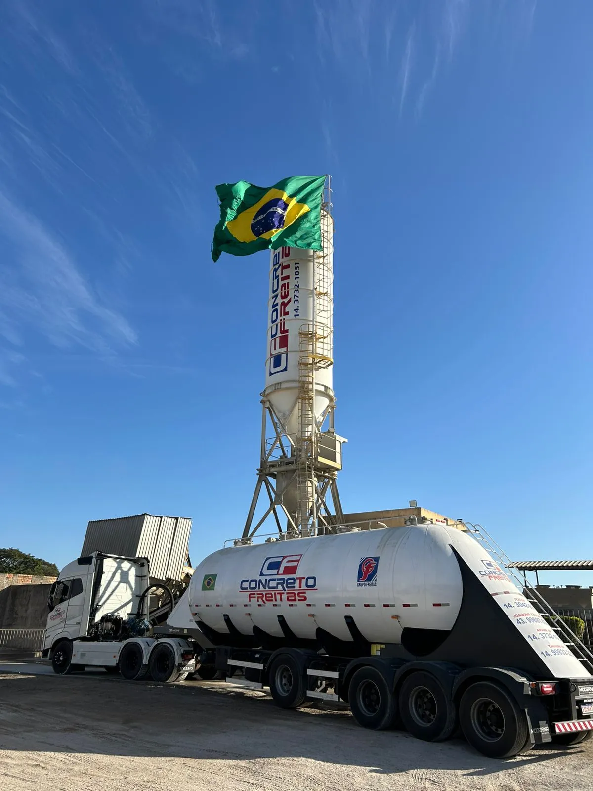 Central dosadora da Concreto Freitas, com silo de cimento e a bandeira do Brasil, e o caminhão de cimento a granel estacionado à frente