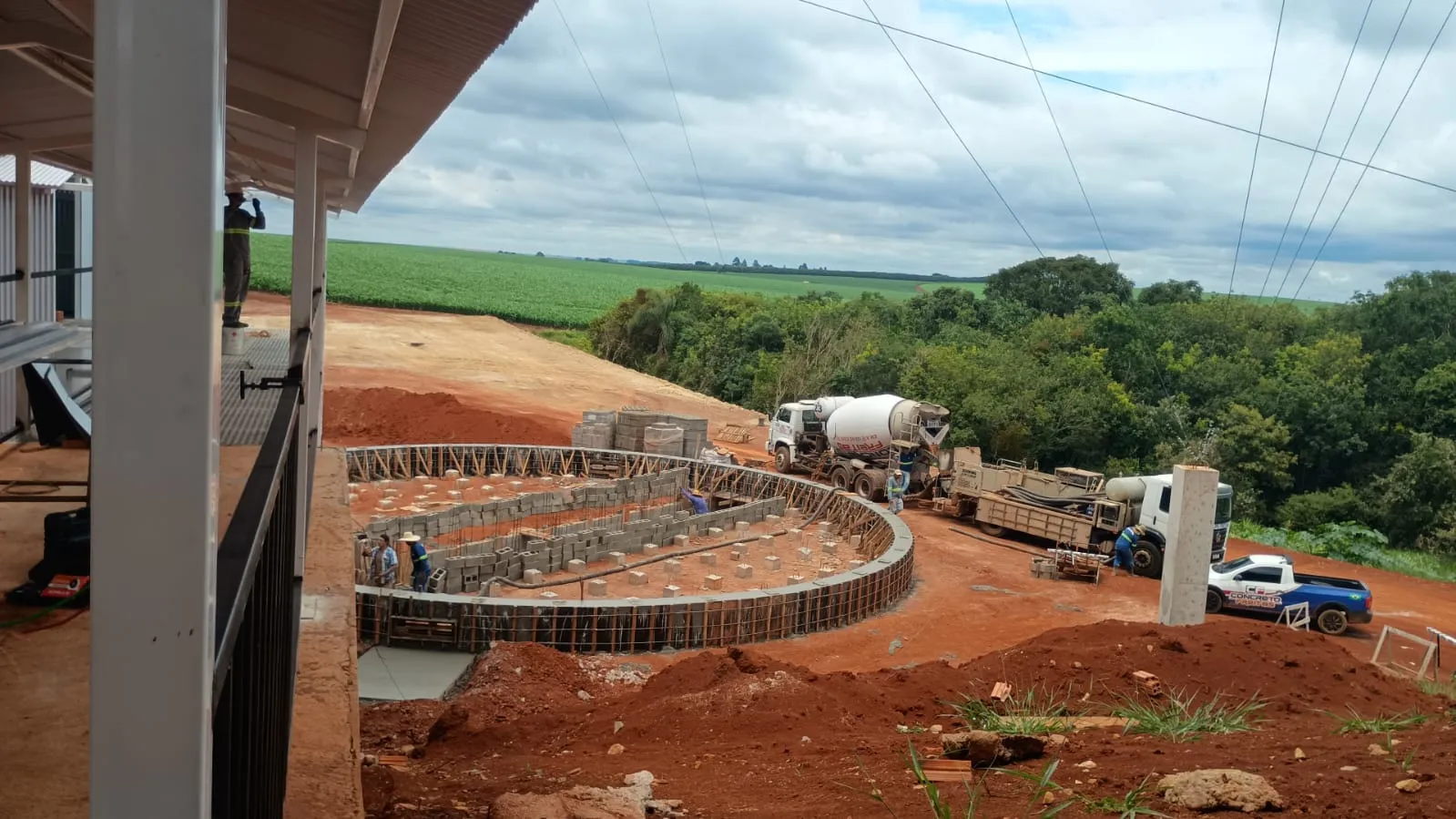 Estrutura circular em fôrmas e armação pronta para concretagem, com caminhão betoneira e bomba de concreto ao fundo